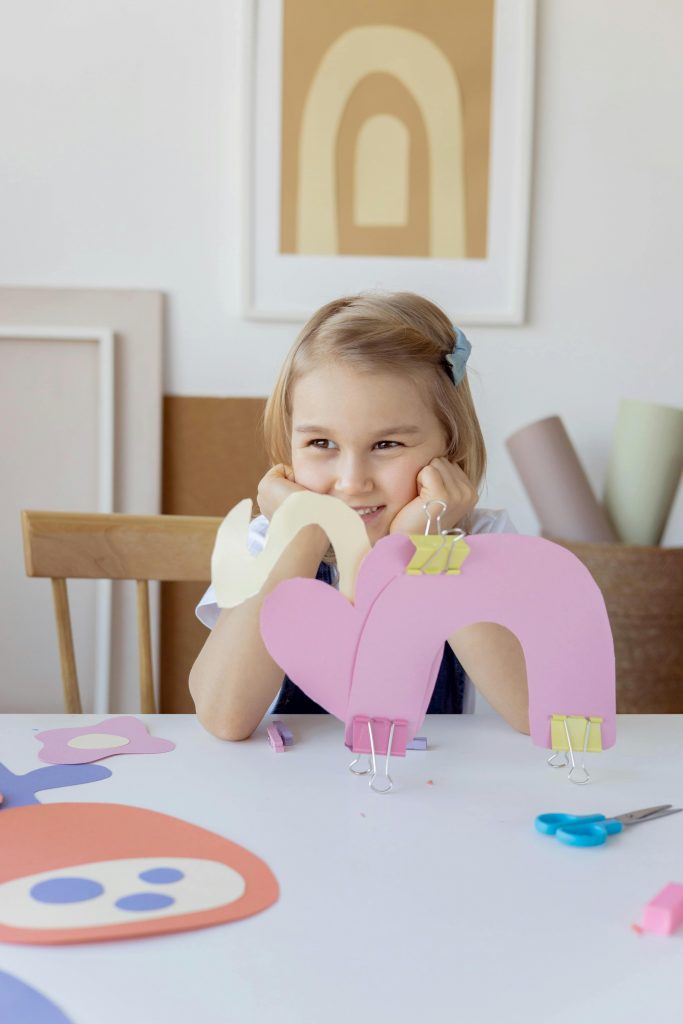 A cheerful child engaged in a fun art project, creating colorful paper crafts at home.
